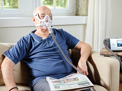 Patient avec PBCO sous ventilation Lumis lisant le journal